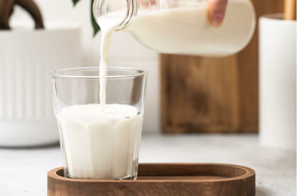 A caregiver pouring a glass of milk to prepare for thickening.