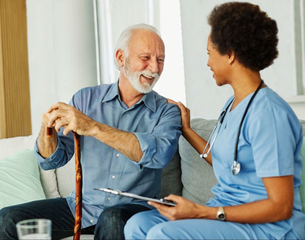 A caregiver in memory care rests her hand on a senior's shoulder while taking him through a test.