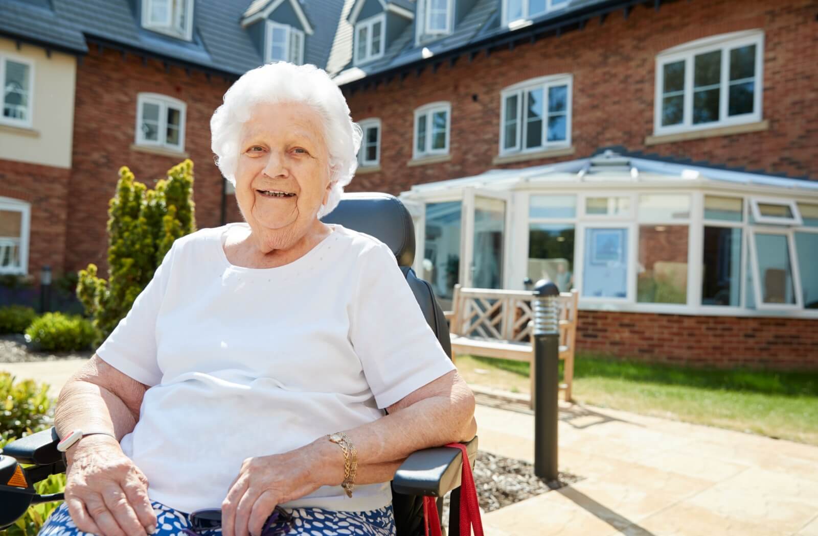 A smiling senior enjoy the sunshine in an outdoor area of their assisted living community