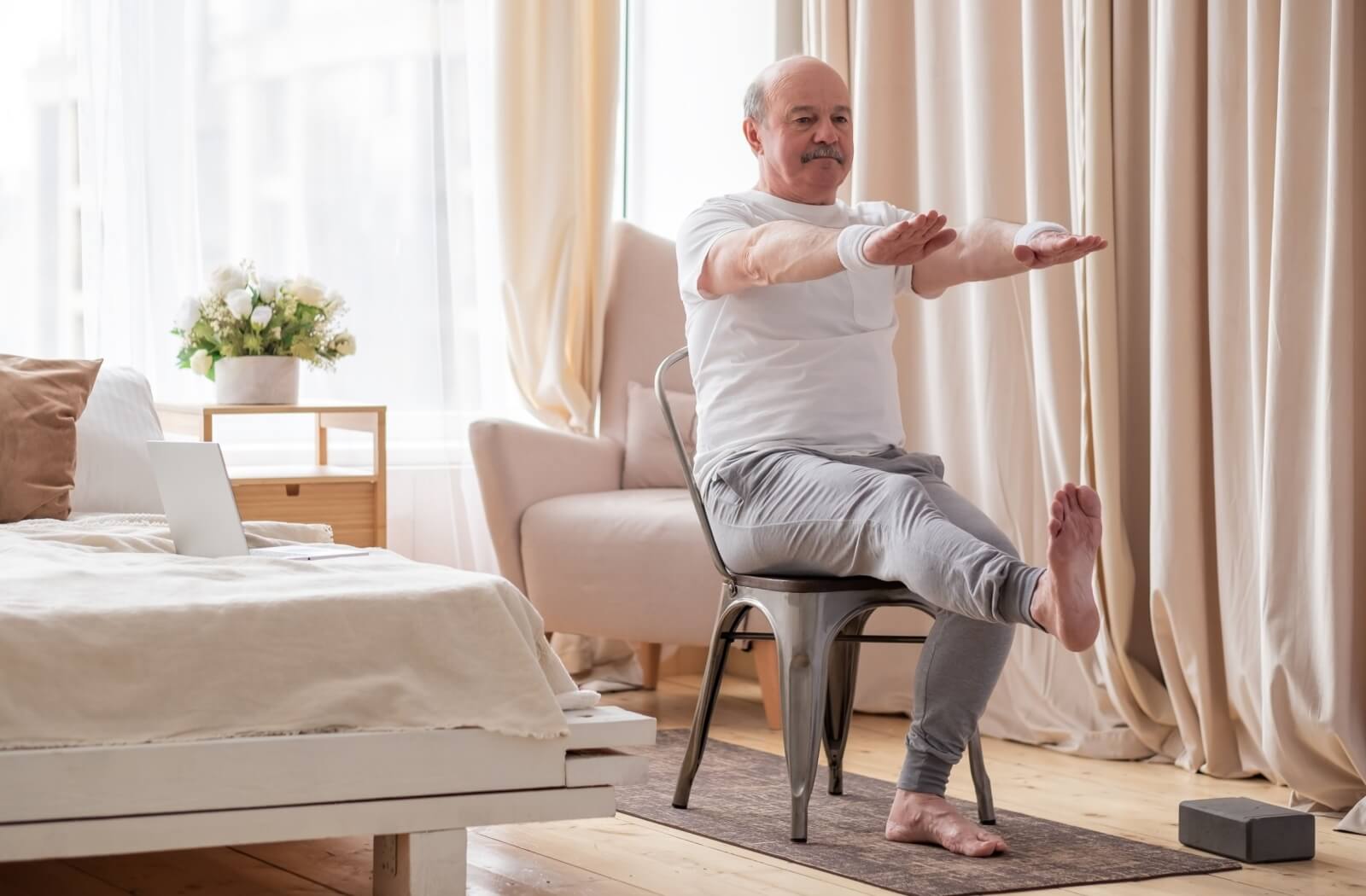 An older adult practicing seated leg lifts in the comfort of their assisted living apartment.