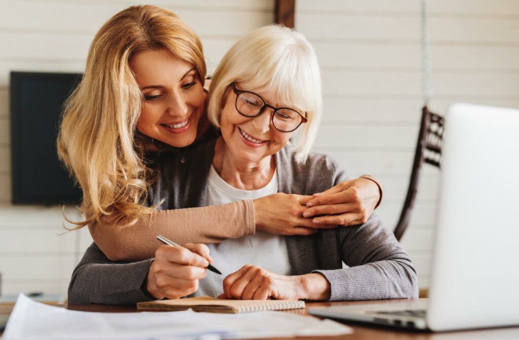 a young person hugs their senior parent who is sitting down 