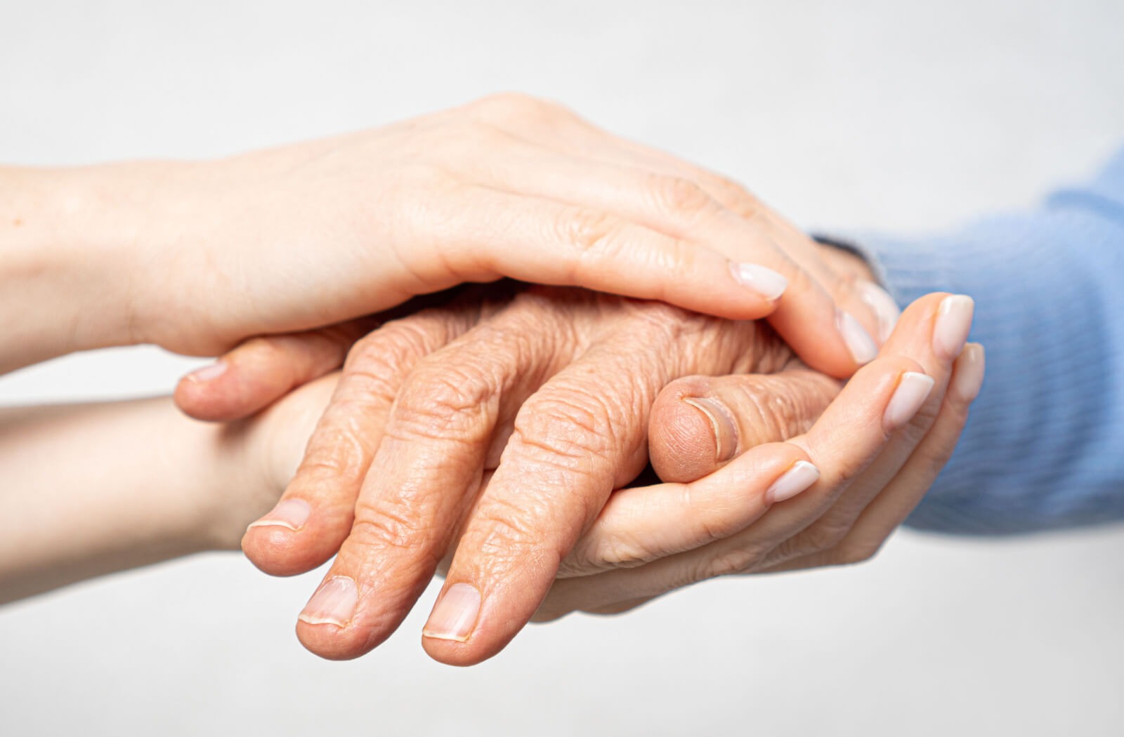 young hands hold senior hands in support