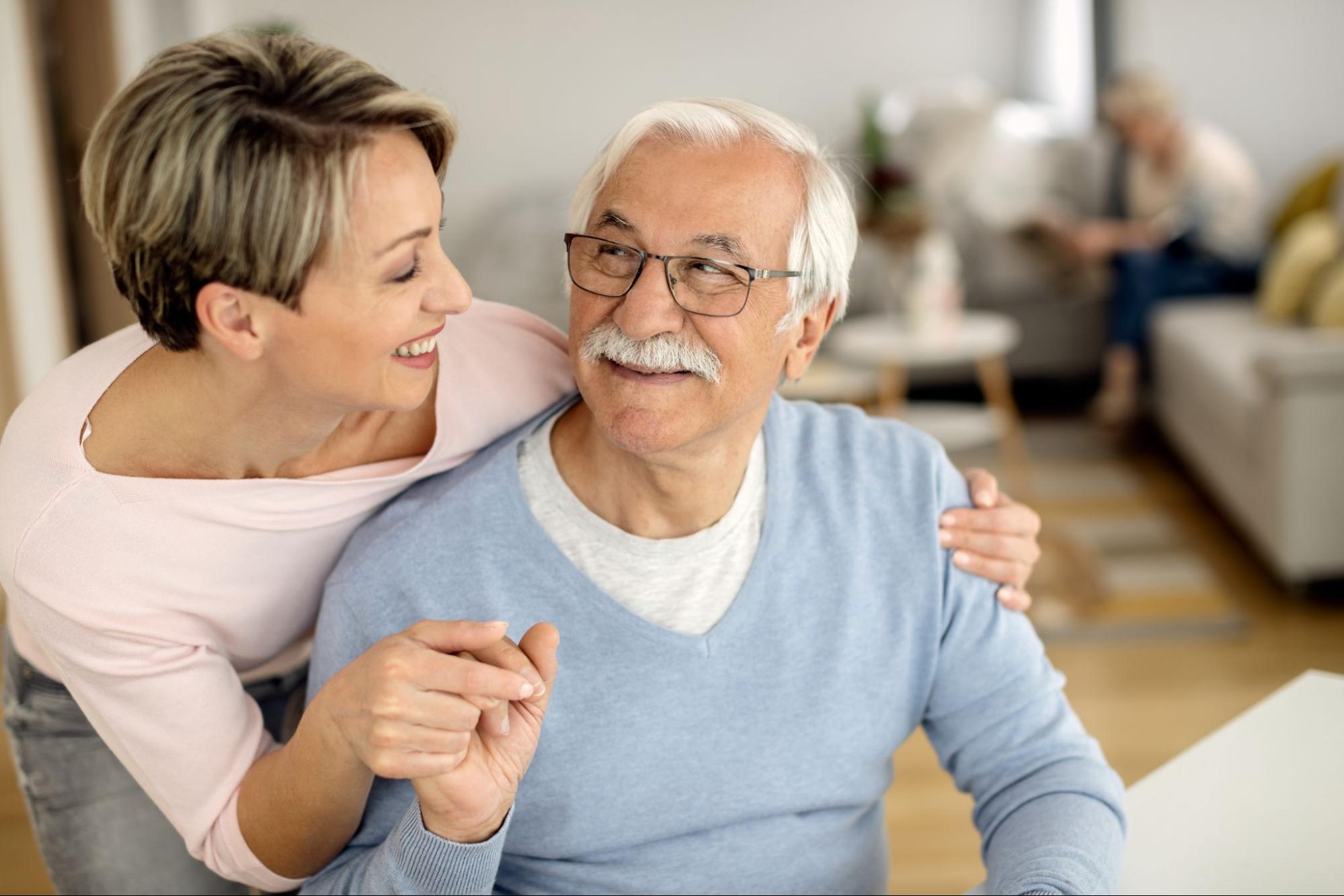 An adult child embracing her older adult parent living in assisted living.