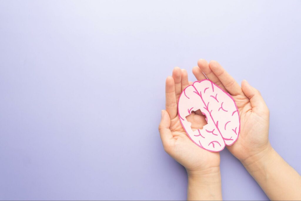 a person holding a puzzle of a brain with one piece missing symbolizing dementia.